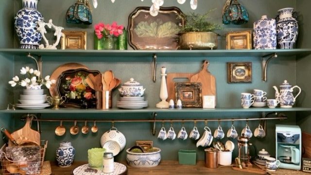 Kitchen styling with copper pot hanger, blue and white tea pots, and wooden accent pieces. 