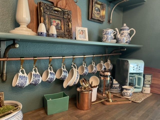 Blue and white tea set hanging from copper pot hanger. 