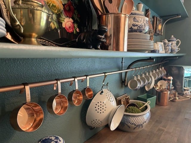 Copper pot hanger with copperware and tea cups. 