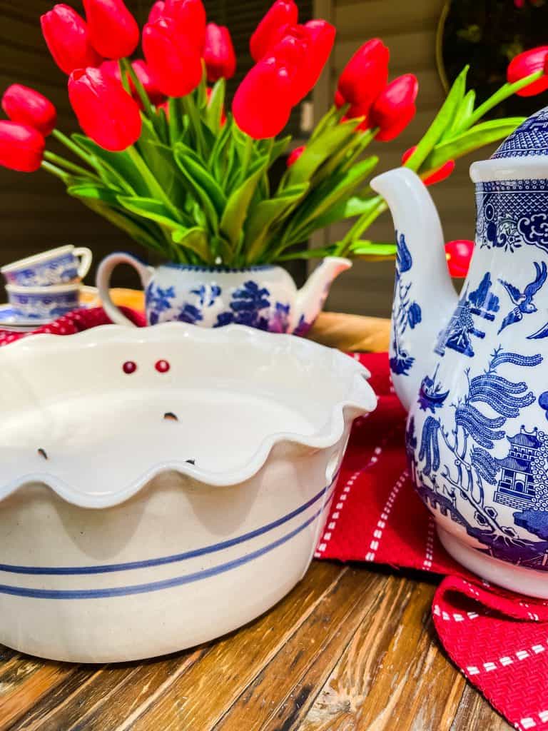 citronella candle with blue and white teapots and red tulips
