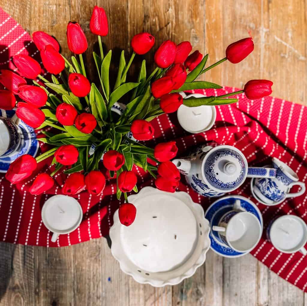 red tulips and blue and white dishes surrounding a diy citronella candle