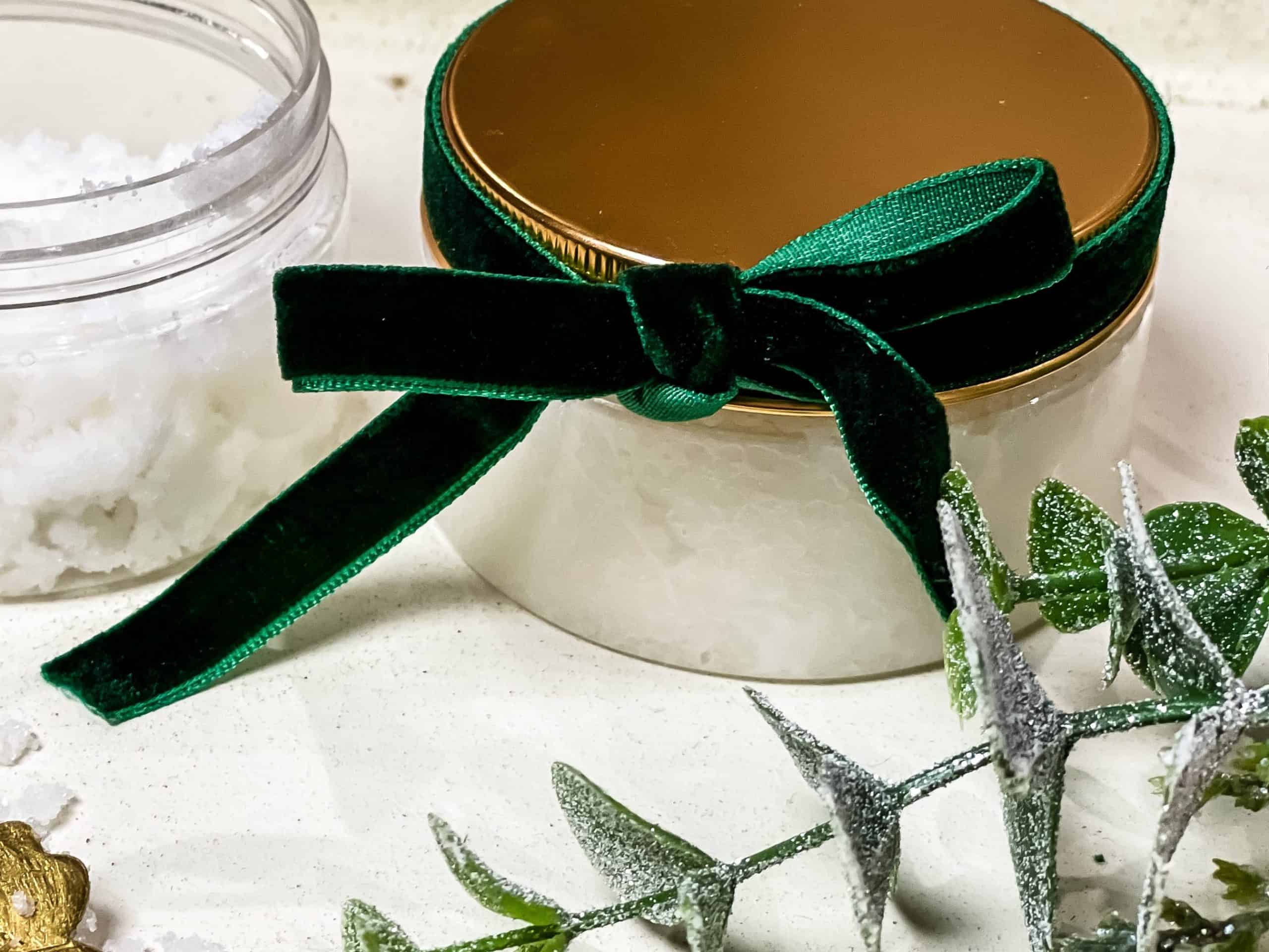 Sugar cookie scrub in a cute clear container topped with a gold lid and wrapped in a beautiful velvet green ribbon. 