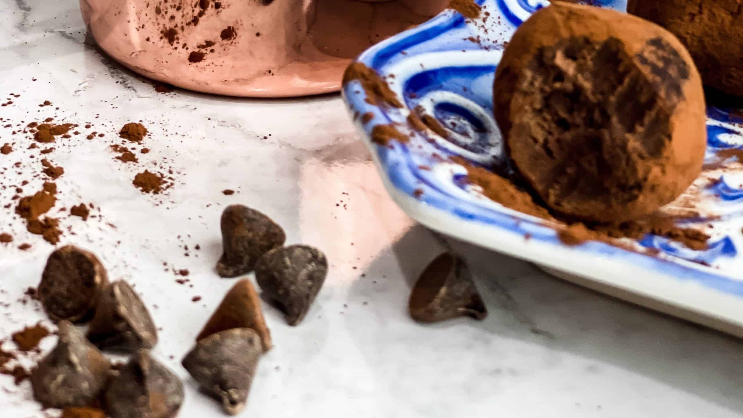 Blue and White dish with homemade Ghirardelli chocolate truffles sitting with a bite out and Ghirardelli chocolate chips. 