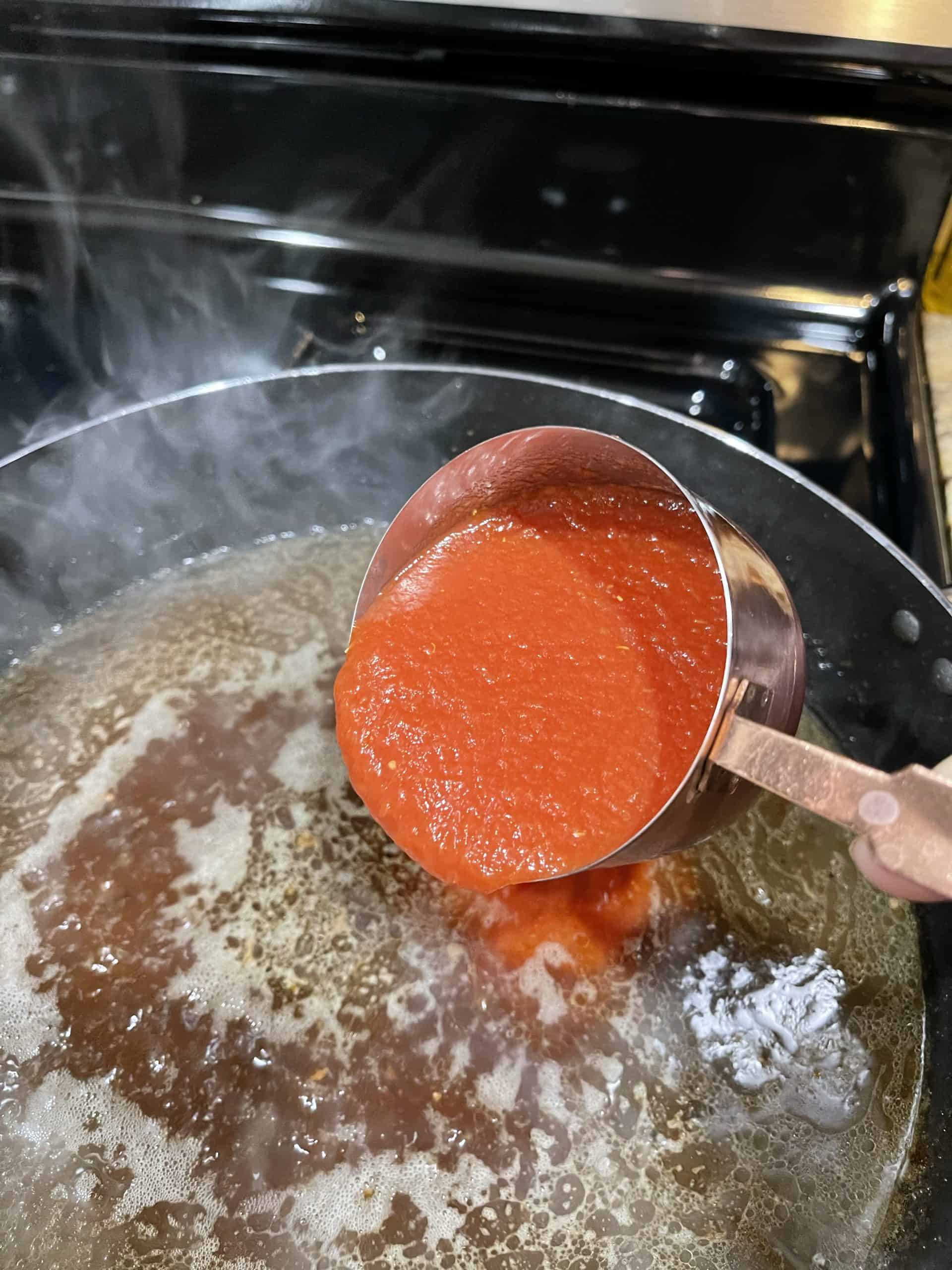 Adding tomato sauce into the broth and soy sauce mixture.