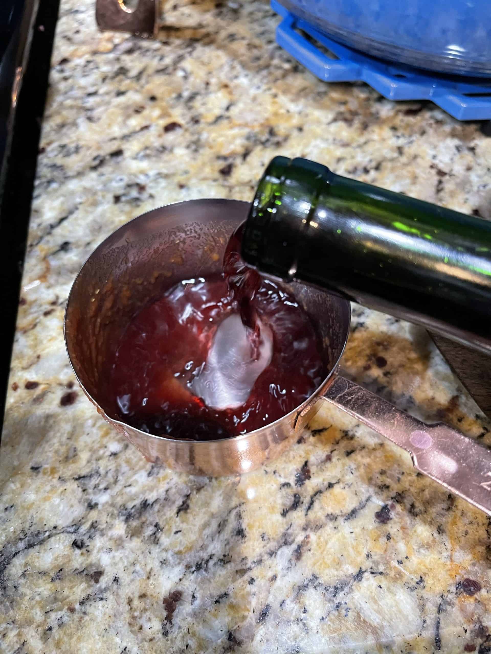 Red wine poured into measuring cup