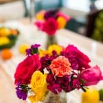 hot pink and yellow roses on a table with oranges , lemons and limes